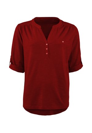 Rote kurzärmelige Bluse mit Henley-Ausschnitt, die drei Knöpfe, eine kleine Brusttasche und aufgekrempelte Ärmel aufweist. Weicher, leichter Stoff.