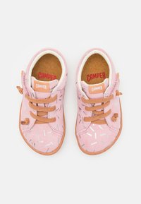 Rosa Wildlederschuhe für Kinder mit braunen Schnürsenkeln und einer Gummisohle, die ein gepunktetes Muster mit silbernen und hellblauen Akzenten aufweisen.