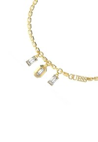 Collana in oro con tre charm geometrici in pietra trasparente e il nome del marchio "GUESS" integrato nel design.