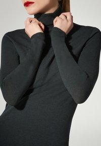 Maglia a collo alto nera realizzata in tessuto a maglia fine, con maniche lunghe e una vestibilità aderente. Texture sottile, stile minimalista.