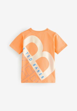 Pomarańczowa bawełniana koszulka z krótkim rękawem, z dużym białym i niebieskim wzorem graficznym, przedstawiającym "TED BAKER" oraz wyraźne logo.