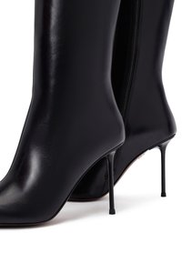 Bottines en cuir noir avec un bout pointu, un talon aiguille fin et une fermeture éclair exposée sur le côté. Texture lisse avec une finition haute brillance.