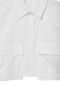 Chemise blanche raccourcie avec un col classique, fermeture par boutons, et deux poches avant avec une texture lisse et un design structuré.