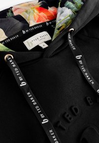 Sort Ted Baker hoodie med blomsterprintfoer, mærkede snore og præget logo på brystet.