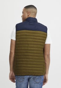 Polstret vest med en marineblå overdel og en olivengrøn underdel, med horisontale sømme og høj krave.