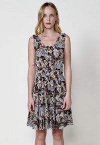 Ärmelloses Kleid mit floralem Muster in Schwarz, Weiß und Orange. Verfügt über einen Rundhalsausschnitt und eine geraffte Taille, die in einen schwingenden Rock übergeht.