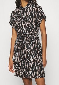 Robe à manches courtes avec col, dotée d'un motif à zigzag noir, rose et blanc ; taille cintrée avec une ceinture ; tissu léger.