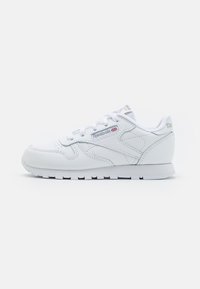 Baskets blanches en cuir, avec un bout rond, un laçage, des côtés texturés et des accents de logo sur la languette et le talon.