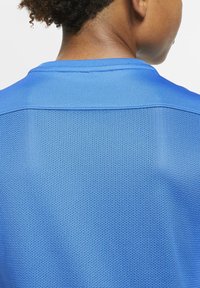 Maglietta sportiva blu realizzata in un tessuto a rete testurizzato e traspirante, con scollatura rotonda e cuciture rinforzate al collo.