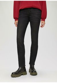 Zwarte denim jeans met een slim fit, met een subtiele textuur. Gecombineerd met zwarte enkellaarsjes met een stevige groene zool.