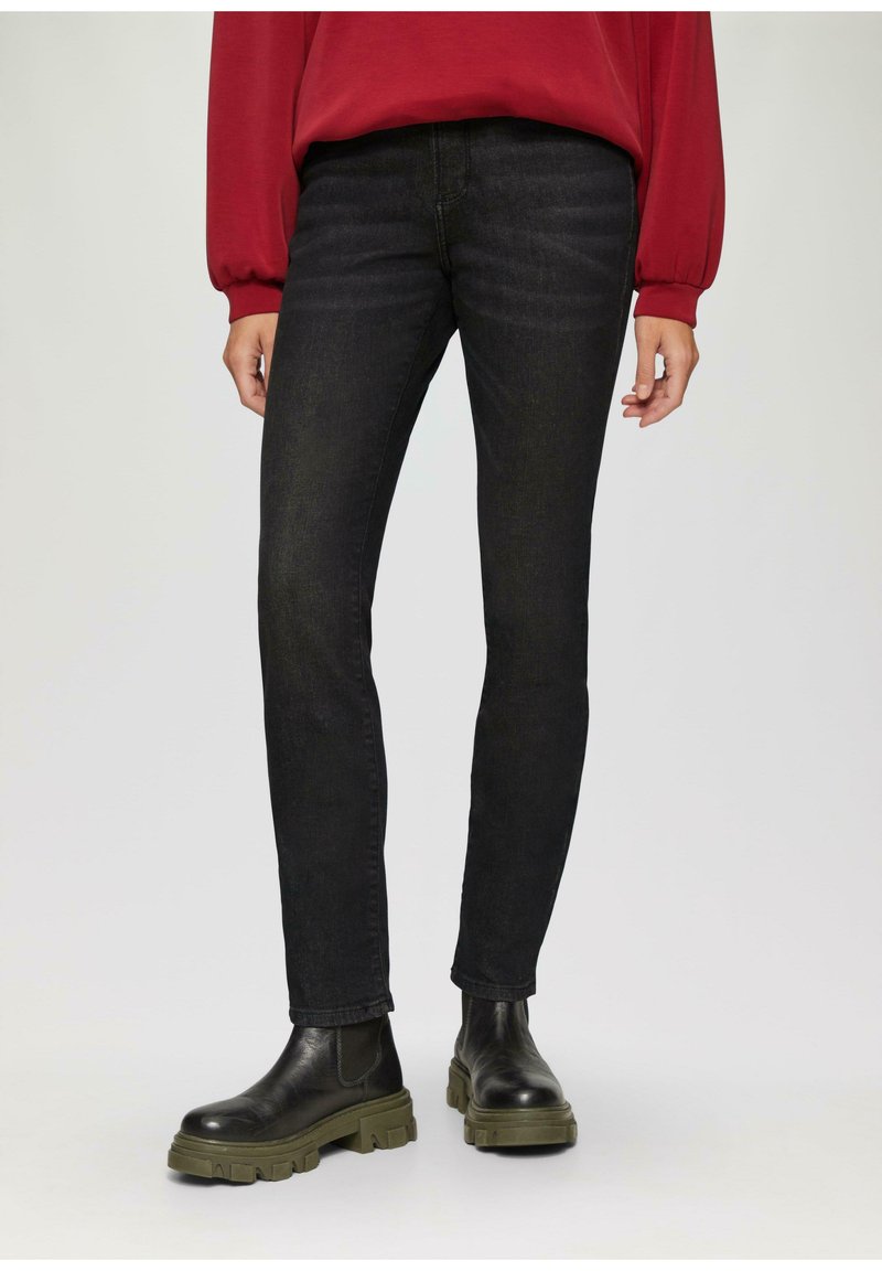 Zwarte denim jeans met een slim fit, met een subtiele textuur. Gecombineerd met zwarte enkellaarsjes met een stevige groene zool.