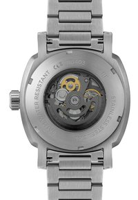 Klocka i rostfritt stål med en genomskinlig baksida som visar upp intrikata guld- och silverväxlar, samt ett texturerat grått metallarmband.