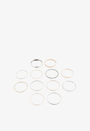 Thirteen thin metal rings in silver and gold tones arranged in a scattered pattern on a white background.
