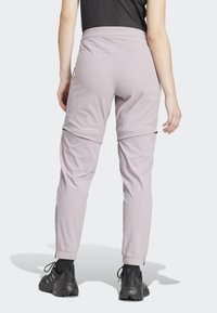 Light purple athletic pants with elasticized waist and cuffs, featuring zippered side vents and a smooth, slightly reflective texture.