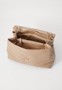 Borsa a mano in pelle beige con texture trapuntata, chiusura con un singolo bottone dorato e doppie catene. Interno aperto con una tasca con zip.