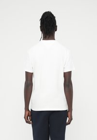 Λευκό T-shirt με κοντά μανίκια, στρογγυλή λαιμόκοψη και ίσιο τελείωμα. Κατασκευασμένο από βαμβάκι, με λεία υφή και απλό σχέδιο.