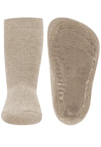 Beige rutschfeste Socken mit strukturierten Gummigriffen an der Sohle, von vorne und von unten gezeigt.