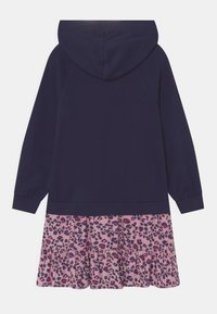 Mikina šatová s kapucí, která má navy vršek a růžovou sukni s černým a fialovým leopardím potiskem. Měkká tkanina s volánkovým lemem.