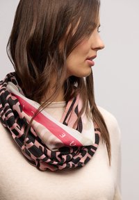 Sciarpa circolare con un mix di motivi rosa, neri e beige. Presenta strisce audaci e accenti testuali, realizzata in un tessuto morbido e leggero.