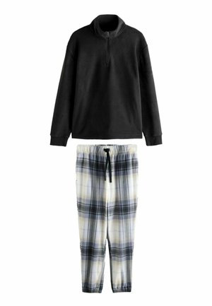 Pull-over en polaire noire à demi-fermeture éclair, associé à un pantalon à cordon blanc et bleu à carreaux, doté d'une taille élastique et de poignets resserrés.