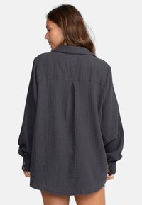 Overgrote donkergrijze blouse van textuurstof, met een klassiek kraag, knoopmanchetten en een yoke-detail op de rug.