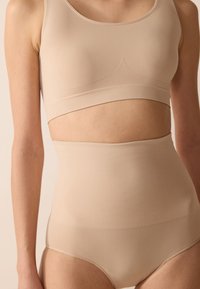 Beige seamless crop top with a rounded neckline and ribbed band. High-waisted, matching brief features smooth texture and minimal seams.