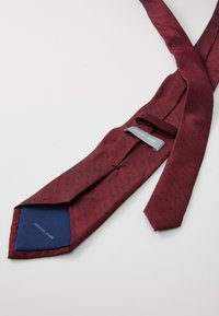 Burgundská kravata s vzorom rybej kosti a malými čiernymi bodkami, s modrou vnútornou stranou a etiketou „Michael Kors.“