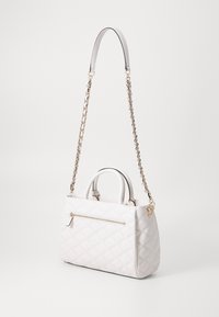 Bolso de mano acolchado en blanco con un acabado texturizado, una correa de cadena desmontable y un bolsillo frontal con cremallera. Cuenta con dos asas superiores y herrajes dorados.