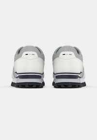 Γκρι και λευκά αθλητικά παπούτσια με υφή στην επάνω επιφάνεια, πάνελ από δίχτυ, και ανθεκτική λαστιχένια σόλα με ναυτικούς τόνους και γκρι μεσαία σόλα.