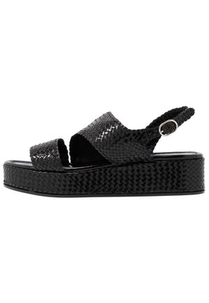 Sandale plateforme noire avec texture tissée, bout ouvert, larges brides croisées et bride arrière réglable avec boucle.