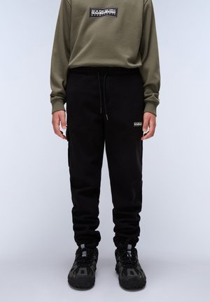 Sorte sweatpants med elastisk talje og sidelommer, parret med en olivengrøn langermet top med et logo-patch.