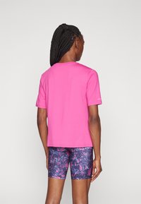 Pink short-sleeve t-shirt made of smooth fabric, paired with navy shorts featuring a colorful abstract pattern.