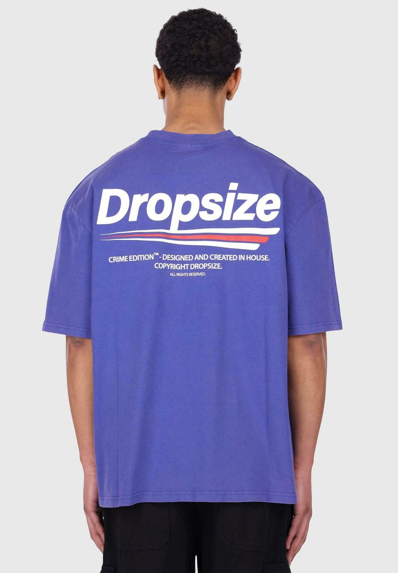 Lila T-Shirt mit kurzen Ärmeln, auf dem Rücken mit dem Text und Logo "Dropsize" versehen, zusätzlich mit Text und einem glatten Baumwollstoff.