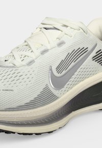 Λευκό παπούτσι τρεξίματος Nike με επάνω μέρος από δίχτυ, γκρι λογότυπο Swoosh, λεπτομερείς μαύρες και γκρι διακοσμητικές πινελιές και μαλακή σόλα.