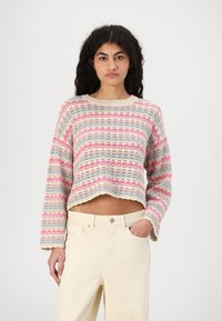 Strikket kort genser med en lys kremfarge som har flerfargede striper i rosa og blått. Bølget kant og vide ermer.