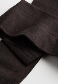 Sorte strikkede benvarmere, der fremviser en blød tekstur, ribbede detaljer i enderne og en glat, sammenhængende overflade.