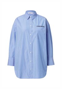 Camicia button-up a righe blu con tasca riportante il testo "STUDIO UNTOLD," colletto classico e maniche lunghe.