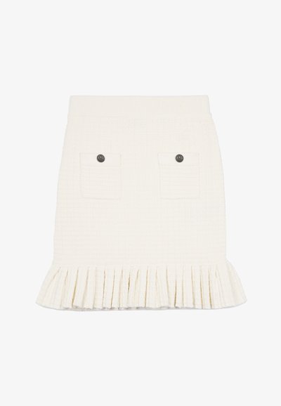 Biała spódnica o textured wykończeniu z falbaną na dole, z dwoma przednimi kieszeniami i ciemnymi guzikami jako akcentami. Materiał ma subtelny wzór kratki.