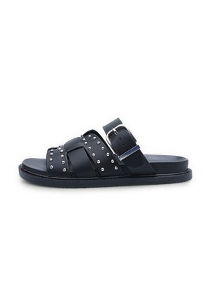 Black slide sandals with crossed straps, metallic studs, and a buckle accent. Material appears smooth; sole is flat and textured.