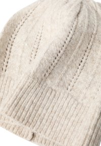 Cream knit beanie made from soft wool, featuring ribbed texture and raised leaf patterns, with a folded cuff at the base.