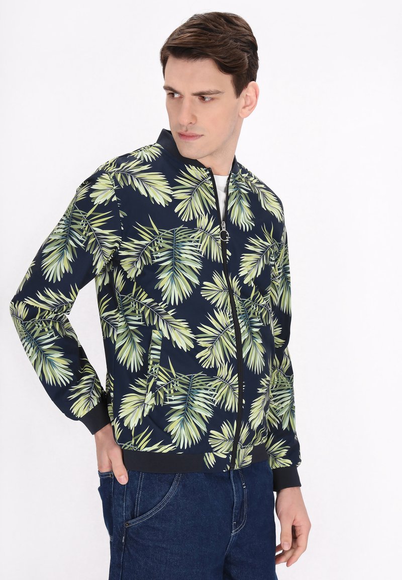 Giacca bomber navy con un motivo di foglie di palma verdi, chiusura frontale con zip, polsini a costine e due tasche laterali. Il materiale sembra liscio e leggero.