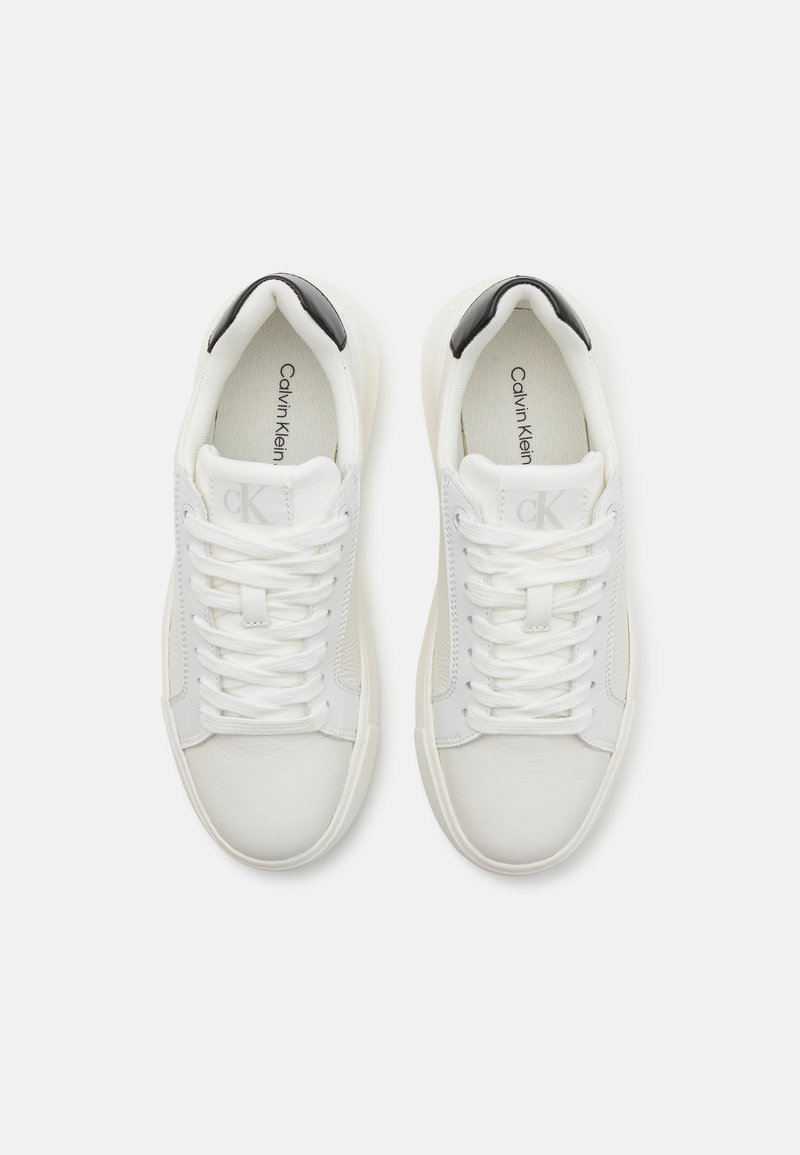 Weiße Ledersneaker mit glatter Textur, die an der Ferse einen schwarzen Akzent und ein ausgeprägtes Markenlogo an der Seite aufweisen.