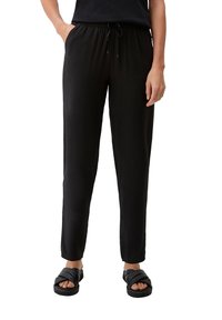 Pantalons de jogging légers et noirs, avec une taille élastique et un cordon de serrage. Présentent des jambes fuselées et des poches latérales. Associés à des sandales noires à enfiler.