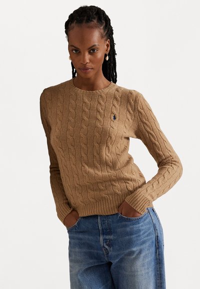 Pull en maille torsadée beige, avec un col rond et des poignets côtelés. Logo brodé discret sur la poitrine gauche.