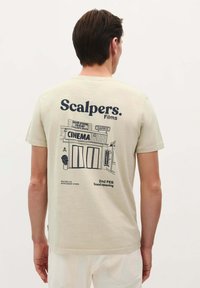 Beige Baumwoll-T-Shirt mit einem bedruckten Kinodesign auf der Rückseite, schwarzem Text und einer grafischen Illustration eines Kinos.