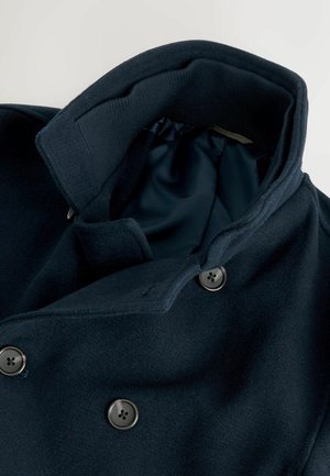 Marineblauer Wollmantel mit großem Kragen, zweireihigem Design und Metallknöpfen. Innenfutter aus glattem Stoff; sichtbare Nähte.