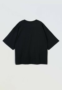 Czarny oversize t-shirt z krótkim rękawem leżący płasko, pokazujący tył, z okrągłym dekoltem i opadającymi szwami ramion.