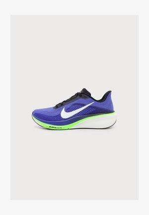 Chaussure de course violette et noire avec un swoosh blanc Nike, un accent néon vert sur la semelle intermédiaire et une semelle blanche épaisse, vue de côté sur fond clair.