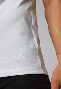White cotton t-shirt with a slim fit, featuring a subtle embroidered "BOSS" logo on the hem. Smooth texture and simple design.