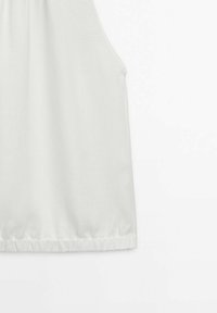 Haut sans manches blanc avec un col froncé et un ourlet élastique. Tissu doux avec une texture lisse, présentant un design minimaliste.